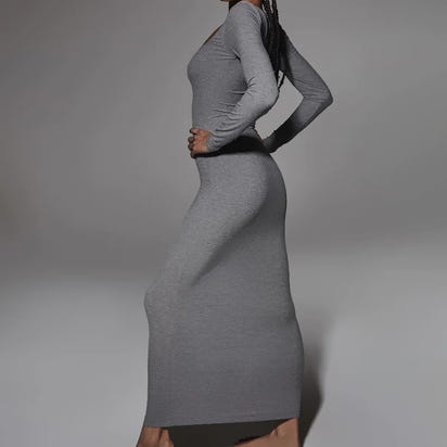 Person wearing a gray dress against a plain background